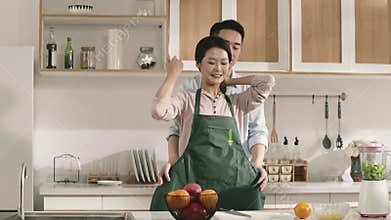 young asian man putting on apron for wife