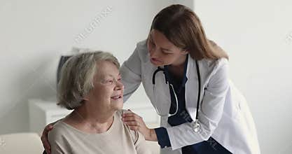 Empathetic geriatric doctor calming down positive smiling senior patient
