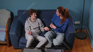 Caring mother talking to her son. A teenager discusses with his parents on a blue sofa at home. Raising a child by a