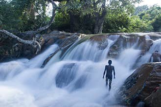 backside view of a man in front of a waterfalls