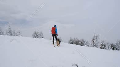 Man hiking with dog in beautiful winter mountain