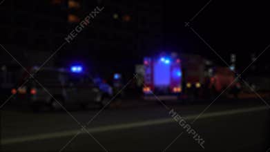 Blurred image of fire trucks with blue flashing lights on.