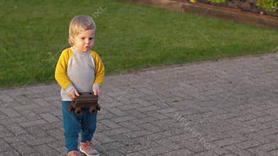 Toddler carries a rusty toy train carriage