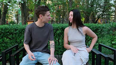 Young man suffers from seasonal allergies while sitting with his girlfriend in a park full of blooming trees. She offers him