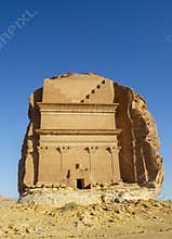The front view of the largest rock tomb Qa?r al-Far?d at Hegra in a sunny day.