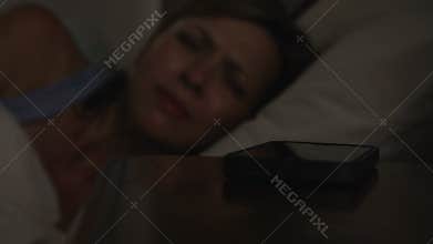 Middle Aged Couple In Bed With Woman Woken By Phone Message