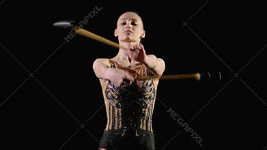 Graceful active female athlete rotating and performing mills with clubs