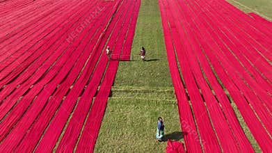 Aerial view of Hundreds of meters of newly dyed, bright red cotton are rolled out to dry in the sun in Narsingdi, Bangladesh.