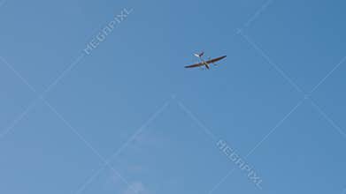 Aerial view of a sleek drone flying against a bright blue sky, showcasing its advanced design and technology