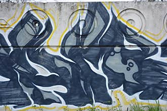 Graffiti depicting the word MAM on white, gray concrete fence.