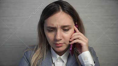 A businesswoman in a suit cries talking on the phone while working. Personal problems in the workplace. Sad woman crying at office
