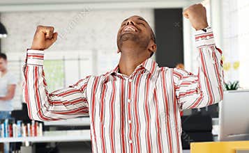 Casual black man celebrating success at office