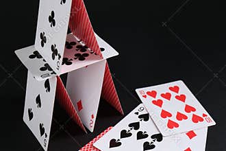House of playing cards on black background, space for text