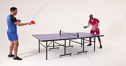 Playing table tennis, two men competing in friendly match indoors