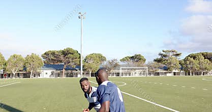 Playing football, two african american men in blue jerseys competing for ball on field