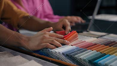 Close up details woman assistant and man designer choosing color fabric samples hands touch textile swatches velvet