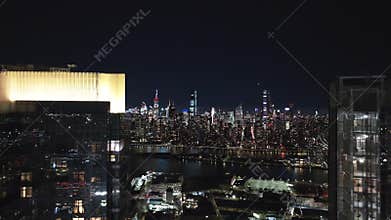 Illuminated New York City skyline captivates at night, with the East River reflecting the vibrant city lights
