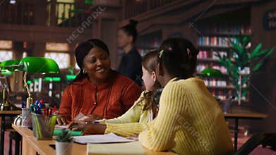 Black teacher mentoring her teen girls students with an assignment