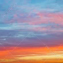 Pastel pink and yellow sunrise clouds in blue sky
