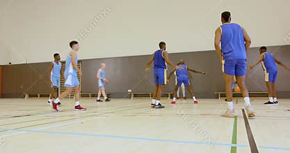 Basketball players competing intensely on indoor court during practice game