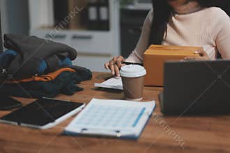 Startup SME small business entrepreneur of freelance Asian woman wearing apron using laptop and box to receive and review orders