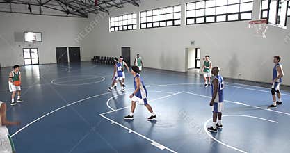 Basketball players competing in gym, focused on game and teamwork