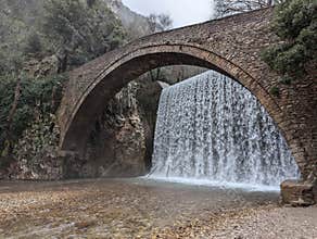 Stone bridge of Palaiokarya with a waterfall behind