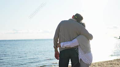Senior mature couple hugging enjoying outdoor recreation walking on beach. Old husband wife embracing with tenderness