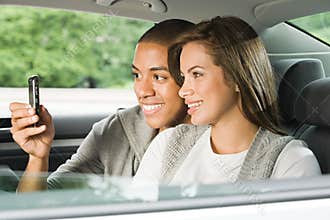 Young couple using a cellular phone in car