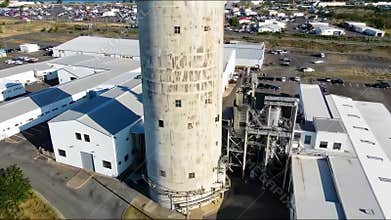 Red car arriving at industrial facility with silo