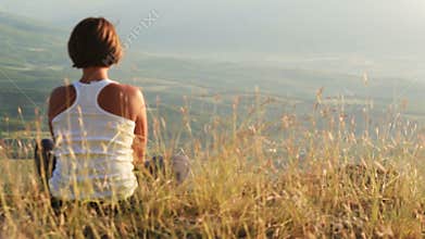 Young girl meets sun on the top of hill