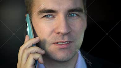 Young successful businessman boss talking on phone close up, man smiling contentedly inside office at workplace in