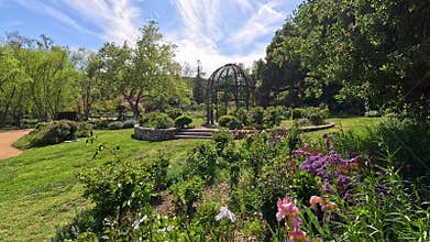 footage of a gorgeous spring landscape with a gazebo, colorful flowers and lush green trees and plants at Descanso Gardens