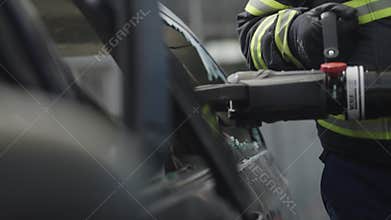 A courageous firefighter, equipped with specialized tools, heroically rescues people trapped in a car accident