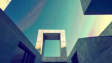 Concrete structures reach towards a hazy sky in geometric patterns, forming an open-air modern building