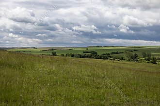 Rolling Hills Landscape with Green Fields and Dramatic Sky