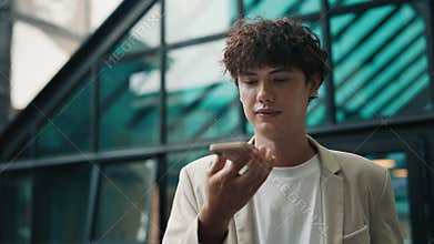 Portrait of businessman recording voice message on phone at office center