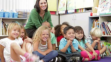 Elementary Age Schoolchildren Sitting On Floor With Teacher
