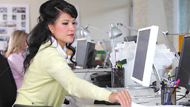 Woman Working At Desk In Busy Creative Office