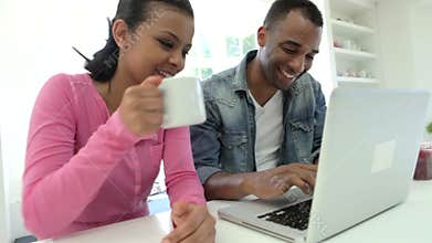Couple Having Breakfast Using Laptop In Kitchen Together