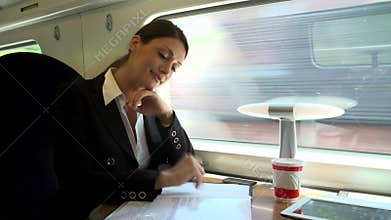 Female Commuter With Coffee On Train Working On Document