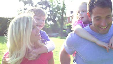 Parents Giving Children Piggyback Rides In Garden