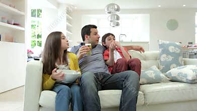 Hispanic Family Sitting On Sofa Watching TV Together