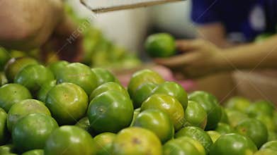 Hands Picking Fresh Green Mandarins at Thai Street Market