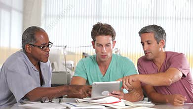 Three Men Using Tablet Computer In Creative Office
