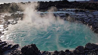 Hot spring water swirling and generating steam in volcanic landscape