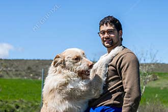 Veterinarian holding happy hunting dog in rural landscape