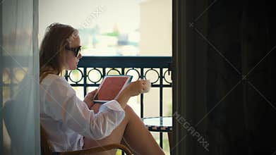 Young woman with touchpad on hotel balcony