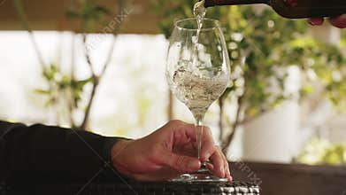 Restaurant Waiter Filling Glass with White Beverage of Bottle to Man at Wine Bar