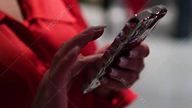 Red shirt texting Woman is holding a cell phone and texting. She has red nails and is wearing a white shirt